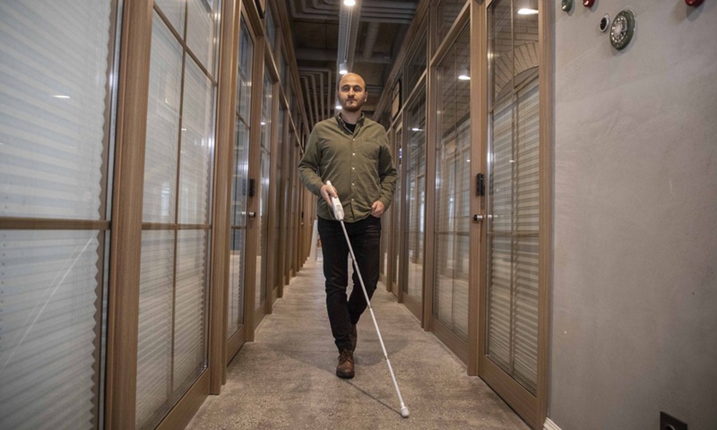 Kursat Ceylan demonstrates the use of the We Walk smart cane, which provides the blind people with navigation assistance via smart technologies, in Istanbul, Turkey on March 2, 2021.(Photo: Xinhua)