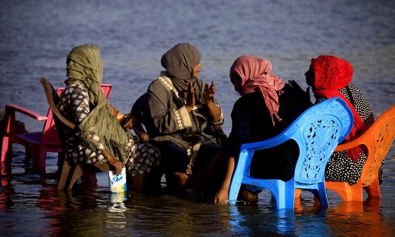 Sudanese women have a chat while sitting on chairs in the water of the Blue Nile in Khartoum, Sudan, March 5, 2021.(Photo: Xinhua)