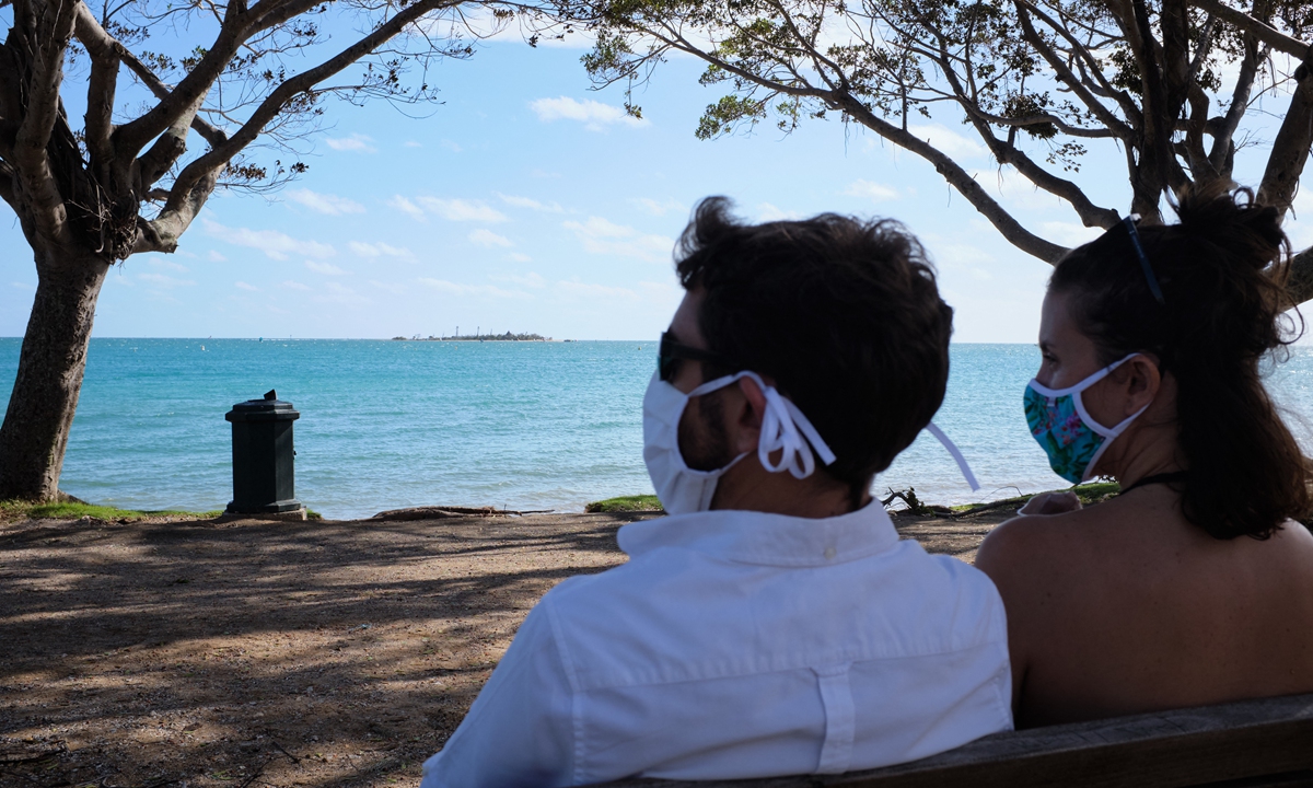 People wear protective face masks as they sit on a bench facing the ocean in Noumea on Monday, as the remote French-controlled Pacific territory of New Caledonia, one of the few places on the planet to have avoided COVID-19, was to go into strict lockdown on Tuesday after detecting nine cases. Photo: AFP