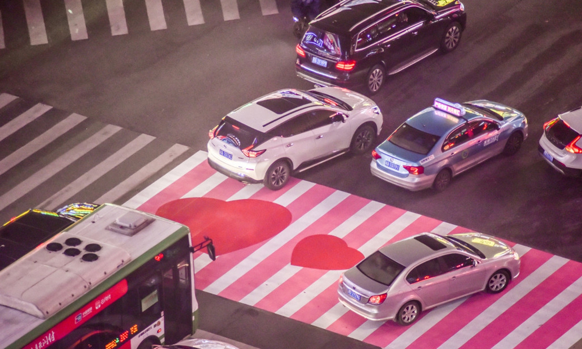A pedestrian crossing at a busy intersection is painted in pink and white, decorated with red heart-shaped patterns, attracting many local residents to take photos in Changsha, Central China's Hunan Province. Photo: IC