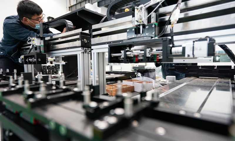 A worker assembles and tests a full-automatic picosecond laser cutting machine at Jiangsu Xianhe Laser Technology Co., Ltd. at Suqian Laser Industrial Park in Suqian City, east China's Jiangsu Province, May 14, 2020.(Photo: Xinhua)