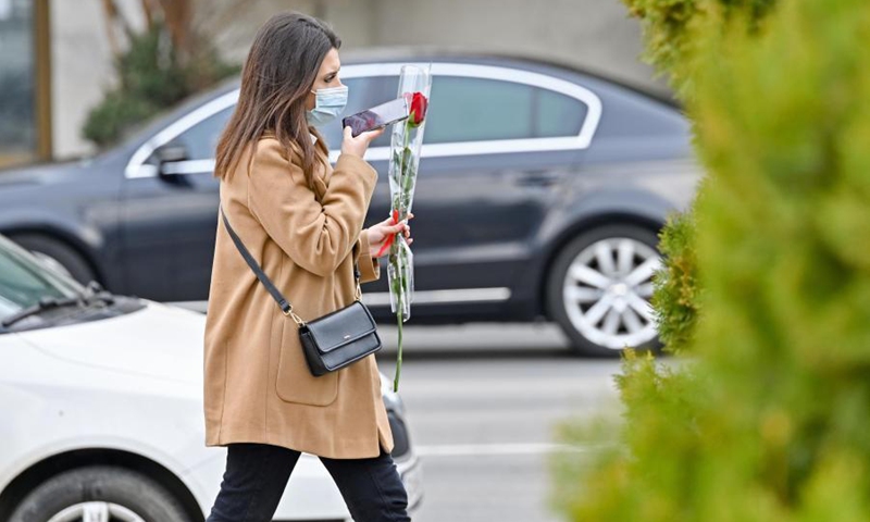 A woman holding a flower walks in the street in Skopje, North Macedonia, on March 8, 2021, on the occasion of the International Women's Day.Photo:Xinhua