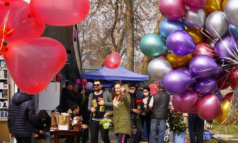 A woman holds a basket of flowers and a balloon in a street in Tashkent, Uzbekistan, March 8, 2021.(Photo: Xinhua)