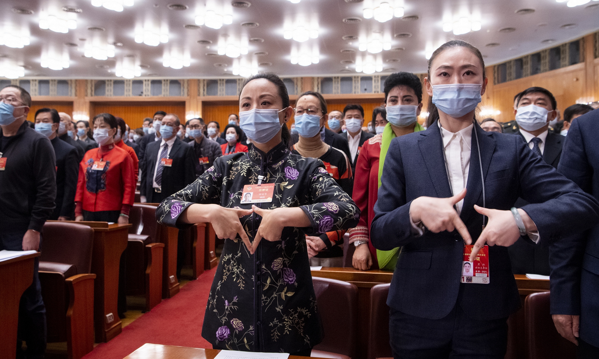 Tai Lihua (center), a member of the 13th National Committee of the Chinese People's Political Consultative Conference (CPPCC) and head of the China Disabled Persons' Art Troupe, and Hei Hong (right), sign language teacher and interpreter for the troupe, sign the national anthem on Wednesday when the fourth session of the 13th National Committee of the CPPCC closed at the Great Hall of the People in Beijing. Photo: VCG