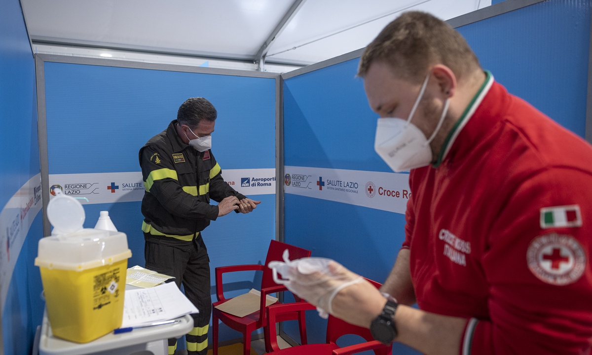 A healthcare worker of the Italian Red Cross (Croce Rossa) gives the AstraZeneca COVID-19 vaccine to a firefighter, as part of COVID-19 vaccination plan for the Police, Carabinieri, and Firefighters in the Lazio region, at the long-stay car park at Fiumicino airport, on February 19, 2021 in Rome, Italy. Photo: VCG