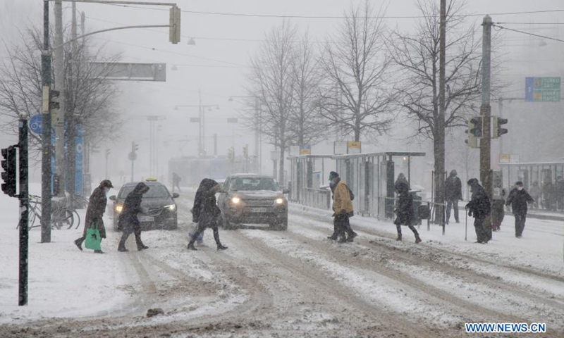 People cross a street in heavy snow in Helsinki, Finland, on March 9, 2021.(Photo: Xinhua)