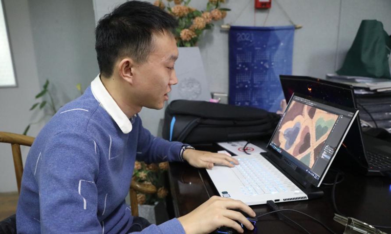 A staff member of a research institute in Lanzhou Jiaotong University designs a dyeing pattern at the institute in Lanzhou, northwest China's Gansu Province, March 9, 2021. The dyes used in this ancient printing and dyeing technique are all natural. Such technique has been listed as a provincial-level intangible cultural heritage.Photo:Xinhua
