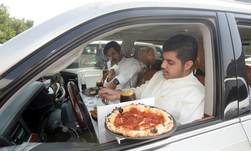 Kuwaiti customers enjoy a meal inside their car outside a restaurant in Kuwait City, Kuwait, on March 10, 2021.(Photo: Xinhua)