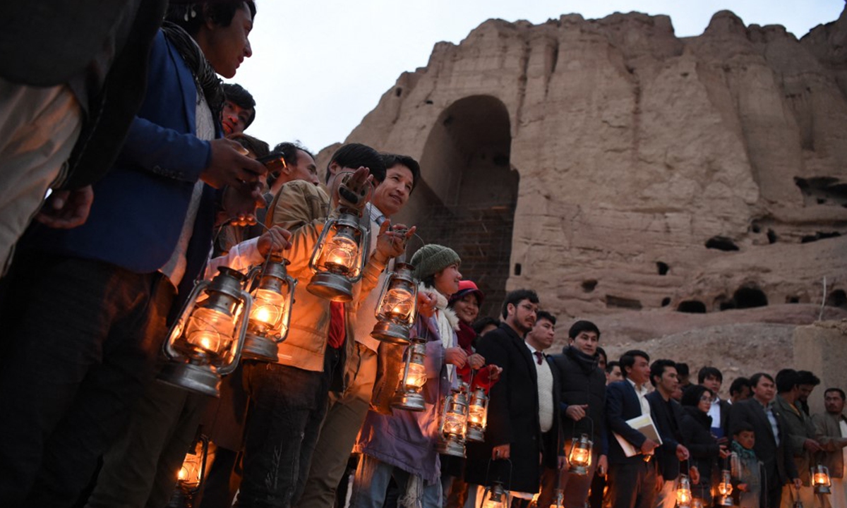 Residents and civil society activists hold lamps on Tuesday as they stand near the site where the Salsal Buddha statue once stood in Bamiyan Province, Afghanistan. Photo: AFP