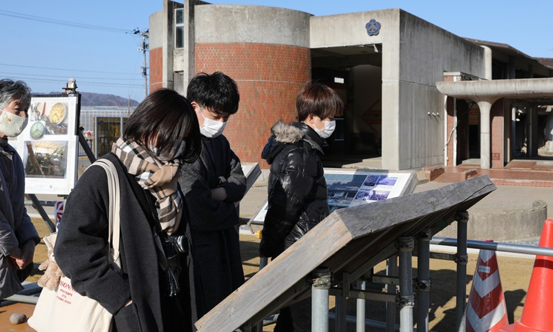 Visitors watch photos of the school before the disaster displayed at the ruins of the Okawa Elementary School in Ishinomaki, Japan, March 9, 2021.(Photo: Xinhua)