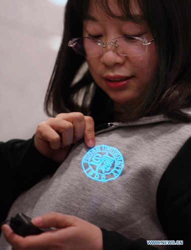 A researcher of Fudan University shows a school symbol made with illuminating fibers in Shanghai, east China, March 10, 2021.(Photo:Xinhua)