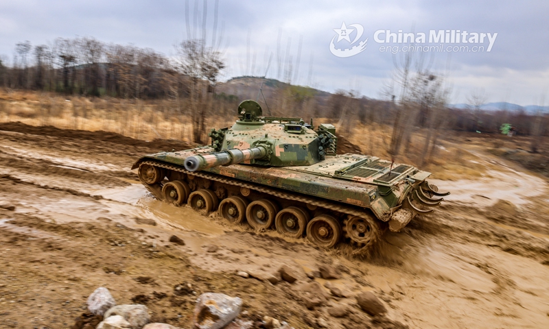 A main battle tank attached to a brigade under the PLA 71st Group Army passes over a shallow trench while rumbling on the muddy road during a coordinated driving skills training exercise on March 1, 2021. Photo: China Military Online