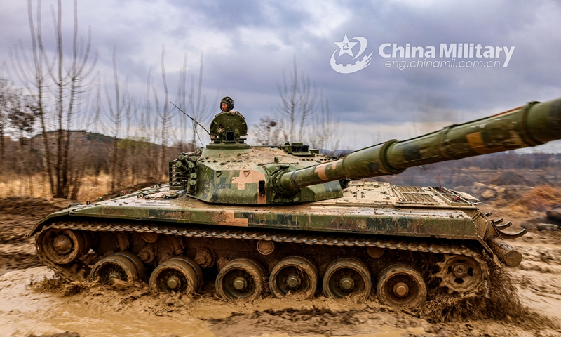 A main battle tank attached to a brigade under the PLA 71st Group Army passes over a shallow trench while rumbling on the muddy road during a coordinated driving skills training exercise on March 1, 2021. Photo: China Military Online
