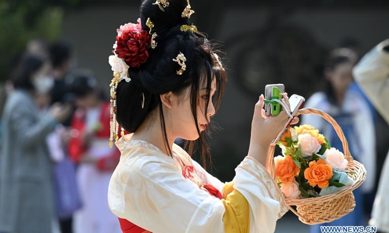 A woman in traditional costume takes photos on the event to celebrate Hua Zhao Jie, or the traditional Flower Festival, at the West Lake Park in Fuzhou, southeast China's Fujian Province, March 14, 2021. A series of activities, such as offering sacrifice to the spring flowers, are held to celebrate the festival in Fuzhou on March 13-14.(Photo: Xinhua)