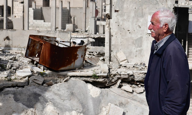 80-year-old Naim Louis stands on the porch of his shattered house in Homs city in central Syria, March 11, 2021.(Photo: Xinhua)