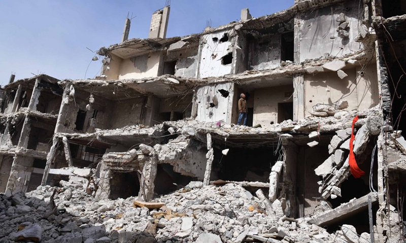Hadi Ghusoun, a retired English teacher in his late 60s, stands on the porch of his shattered home in Homs city in central Syria, on March 11, 2021.(Photo: Xinhua)