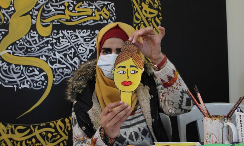 A Palestinian woman with hearing impairment displays a drawing she made for an animated cartoon at Youths' Mettle institution in al-Mughazi refugee camp in the central Gaza Strip on March 7, 2021.(Photo: Xinhua)