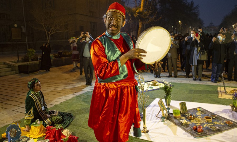 A man wearing traditional dress plays traditional music beside Nowruz decorations displayed in a street in Tehran, Iran, on March 15, 2021.(Photo: Xinhua)
