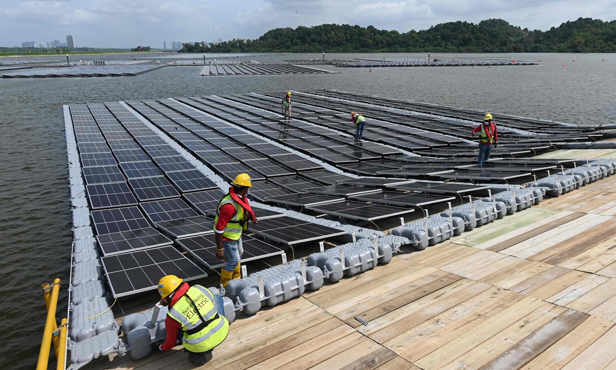Workers assembling solar panels on the shore of the Tengeh reservoir as part of the constuction of a floating solar power farm in Singapore on February 3, 2021. Photo: VCG