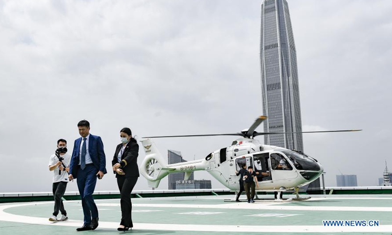 A passenger (C, front) gets off a helicopter which has just completed its maiden flight in a newly introduced airport shuttle service and landed on a helipad in downtown Shenzhen, south China's Guangdong Province, March 18, 2021.(Photo:Xinhua)