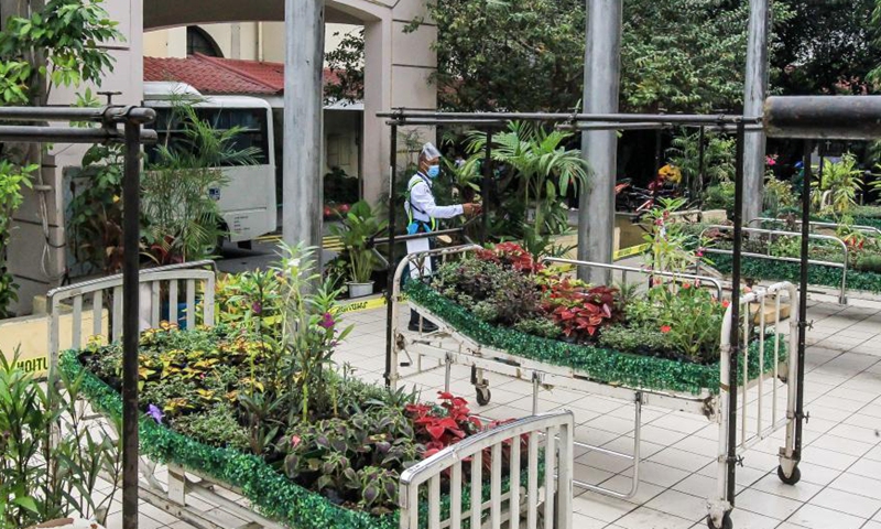 A security guard looks at the art installation Whispering Flower Beds at the University of the Philippines - Philippine General Hospital in Manila, the Philippines on March 18, 2021. The art installation consists of various plants on hospital beds in honor of the Philippines' medical frontliners who died while attending to COVID-19 patients.Photo: Xinhua