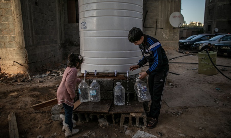 Displaced children fill water containers from a well in a building complex under construction, where hundreds of displaced families live, in Tripoli, Libya, March 2, 2020. (Photo by Amru Salahuddien/Xinhua)