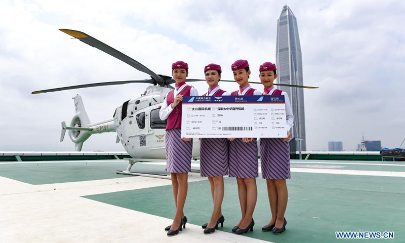 Flight attendants hold a large-size air ticket at the maiden flight ceremony of a newly introduced airport helicopter shuttle service on a helipad in downtown Shenzhen, south China's Guangdong Province, March 18, 2021.(Photo:Xinhua)