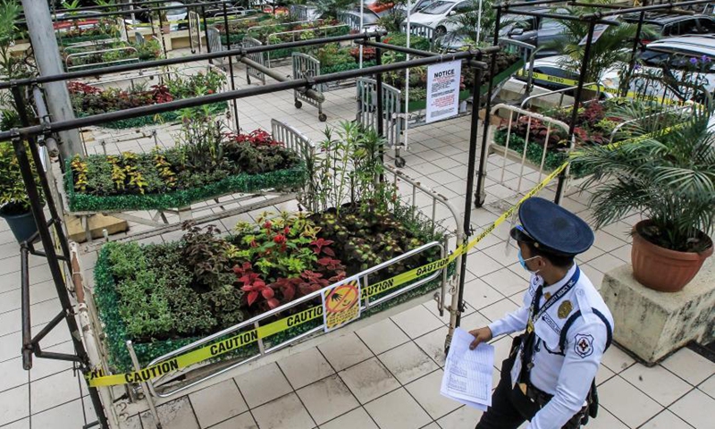 A security guard looks at the art installation Whispering Flower Beds at the University of the Philippines - Philippine General Hospital in Manila, the Philippines on March 18, 2021. The art installation consists of various plants on hospital beds in honor of the Philippines' medical frontliners who died while attending to COVID-19 patients.Photo: Xinhua