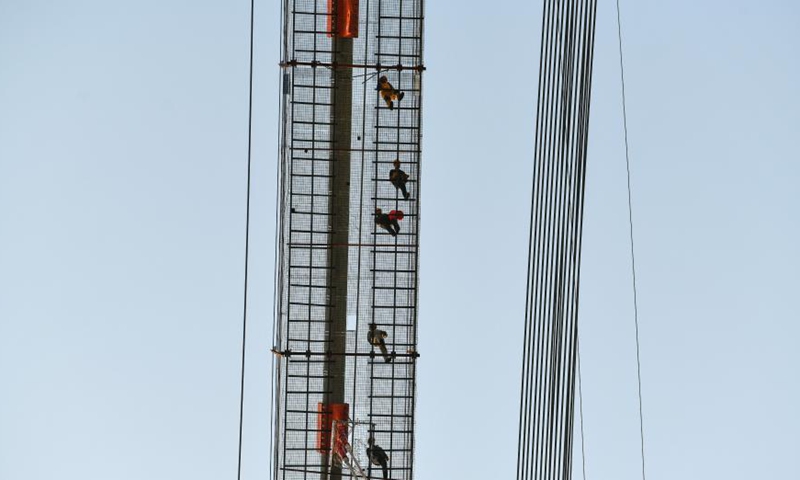 Workers walk on a catwalk at the construction site of the Yangbaoshan grand bridge of Guiyang-Huangping Highway in southwest China's Guizhou Province, March 17, 2021. With a main span of 650 meters, the grand bridge stretches 1,112 meters in length. Currently, the construction of the bridge has entered the final stage of steel truss beam installation. Photo: Xinhua