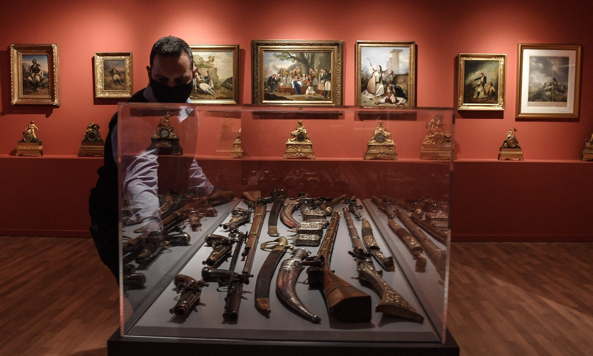 A museum employee bcloses a case displaying weapons in the new museum dedicated to the Philhellene foreign volunteers who fought and died for Greece on March 12, 2021. Photo: VCG