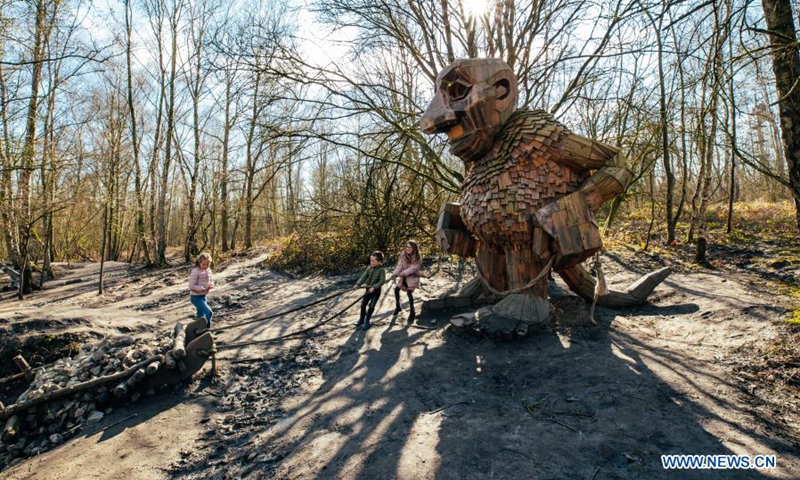 Children play around a troll at the De Schorre forest park in Boom, Belgium, March 20, 2021. Danish artist Thomas Dambo and his team built seven giant trolls from reclaimed wood at the De Schorre forest park in northern Belgium in 2019. These giant wooden sculptures are dotted around the forest.(Photo: Xinhua)