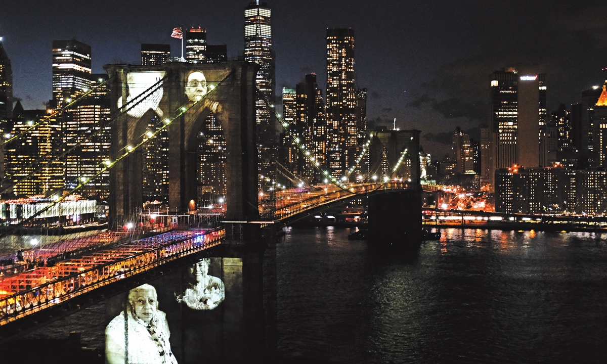 Faces of victims of COVID-19 are projected onto the Brooklyn Bridge during a memorial service called 