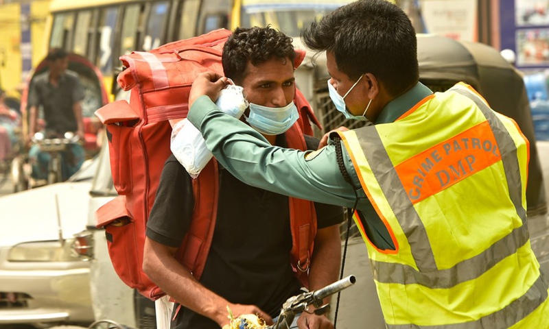 A policeman gives a mask to a rickshaw puller on a street in Dhaka, Bangladesh, March 21, 2021.(Photo: Xinhua)