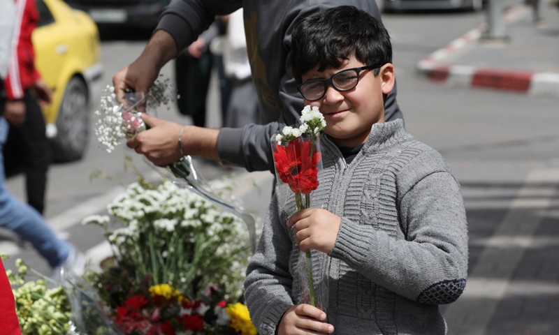 A Palestinian boy buys flowers on the occasion of Mother's Day in the West Bank city of Nablus, March 21, 2021.(Photo: Xinhua)