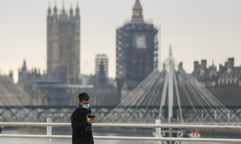 A man walks along the Waterloo Bridge backdropped by the Houses of Parliament in London, Britain on Dec. 29, 2020. (Photo: Xinhua)