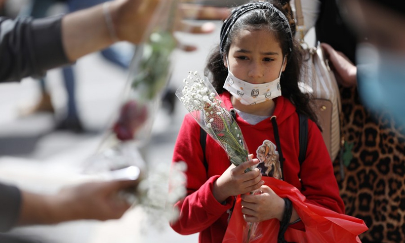 A Palestinian girl buys flowers on the occasion of Mother's Day in the West Bank city of Nablus, March 21, 2021. (Photo: Xinhua)
