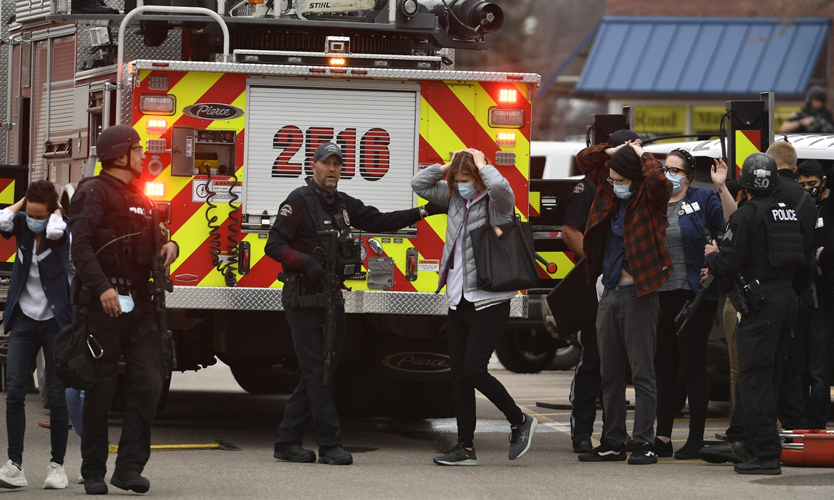 People who were inside the King Soopers supermarket come out of the store with their hands on their heads escorted by police and SWAT members after a mass shooting on Monday in Boulder, Colorado, US. The gunman killed 10 people, including a police officer who responded to the shooting. Photo: VCG