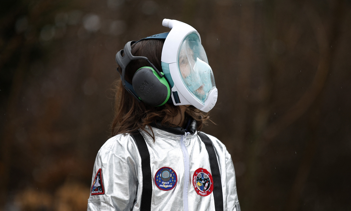 A student at the Ecole Vivalys elementary school in Switzerland, wearing a spacesuit costume, follows a self-made paper rocket during their project 