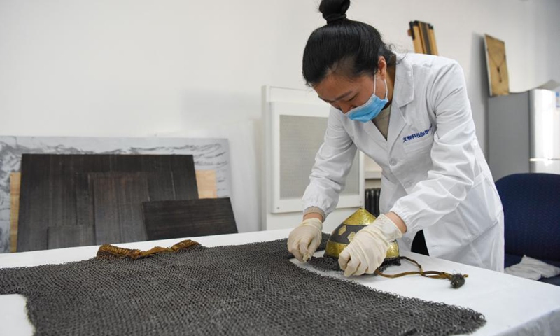 A staff arranges a restored silk robe at the Museum of Xinjiang Uygur Autonomous Region in Urumqi, northwest China's Xinjang Uygur Autonomous Region, March 19, 2021. Northwest China's Xinjiang Uygur Autonomous Region has restored 118 prominent antique items under five restoration projects lasting three years.  (Xinhua)