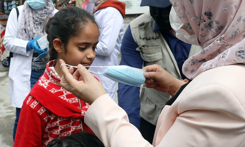 A medical worker helps a girl wear face mask during a COVID-19 awareness and detection campaign in Baghdad, Iraq on March 23, 2021.(Photo: Xinhua)