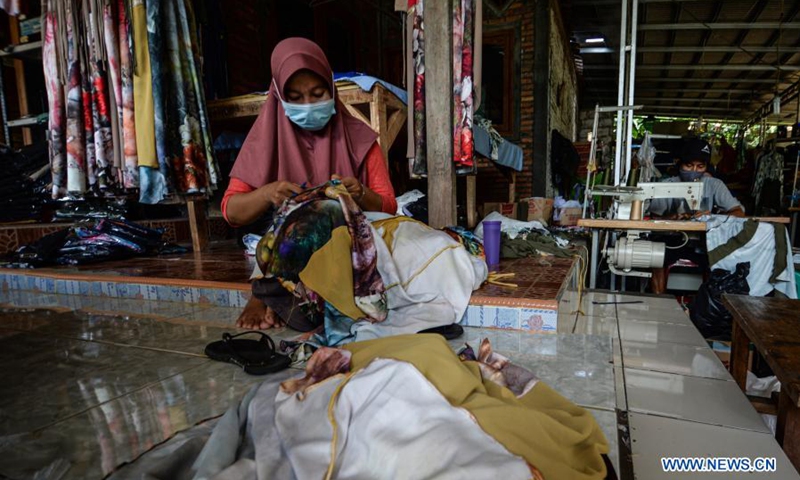 Workers wearing face masks process clothes at the NCK Textile home factory at Curug village in Bogor, West Java, Indonesia, on March 23, 2021. NCK Textile produces clothes to orders from local markets, and provides job opportunities to people in its neighborhood.(Photo: Xinhua)