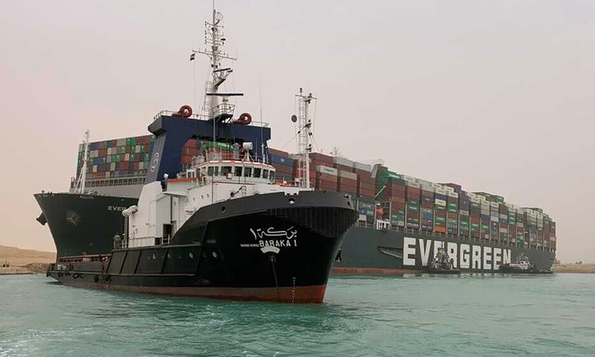 A tug navigates near ultra-large container ship the Ever Given which is operated by Evergreen Marine Corp based in the island of Taiwan,with its bow stuck into the bank of the Suez Canal in Egypt on Wednesday. The vessel turned sideways amid stormy weather, blocking traffic in the crucial East-West waterway for global shipping. An Egyptian official warned on Wednesday it could take at least two days to move the ship. Photo: VCG