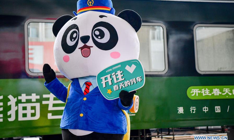 A mascot waves near the panda train in southwest China's Sichuan Province, March 24, 2021. China's first panda-themed tourist train panda train started trial run in Sichuan on Wednesday and will start operation on March 28. Transformed from a normal train, the panda train features upgraded standards inclucing 5G wireless network coverage, music and video entertainment system, restaurant and bar, chess and card room and private toilets with constant temperature shower in sleeping carriages.(Photo: Xinhua)