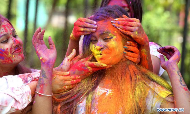 an indian girl has her face smeared with colored powder during