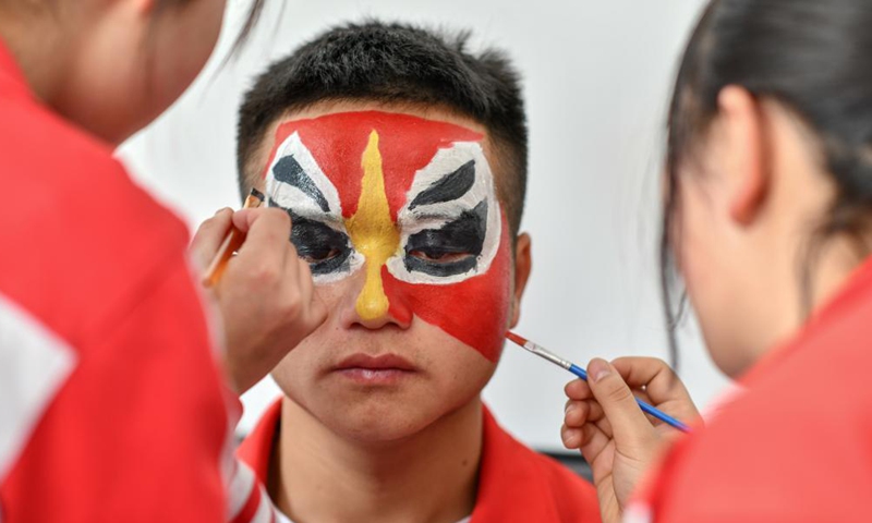 Students draw facial makeup for a student before rehearsal at the No. 3 Middle School of Longli County, Qiannan Buyi and Miao Autonomous Prefecture, southwest China's Guizhou Province, March 23, 2021. In order to pass on and protect the traditional opera Taiping Huadengxi of Longli County, the No. 3 Middle School of Longli County has invited inheritors of the opera to give regular lessons to students (Xinhua)