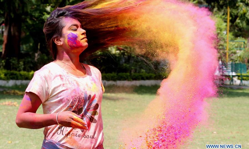 an indian girl has her hair smeared with colored powder during