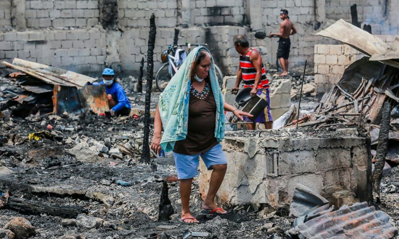 Residents search for their belongings from their charred homes after a fire at a slum area in Rizal Province, the Philippines on March 26, 2021. The Philippine Bureau of Fire Protection said that the fire is believed to have started from one of the houses that was being used as a garment manufacturing area, leaving more than 170 families homeless in the fire.Photo:Xinhua