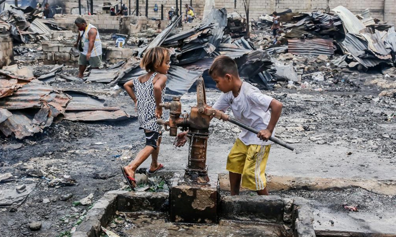 Residents search for their belongings from their charred homes after a fire at a slum area in Rizal Province, the Philippines on March 26, 2021. The Philippine Bureau of Fire Protection said that the fire is believed to have started from one of the houses that was being used as a garment manufacturing area, leaving more than 170 families homeless in the fire.Photo:Xinhua