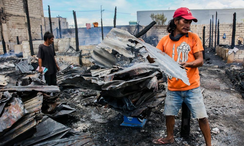 Residents search for their belongings from their charred homes after a fire at a slum area in Rizal Province, the Philippines on March 26, 2021. The Philippine Bureau of Fire Protection said that the fire is believed to have started from one of the houses that was being used as a garment manufacturing area, leaving more than 170 families homeless in the fire.Photo:Xinhua
