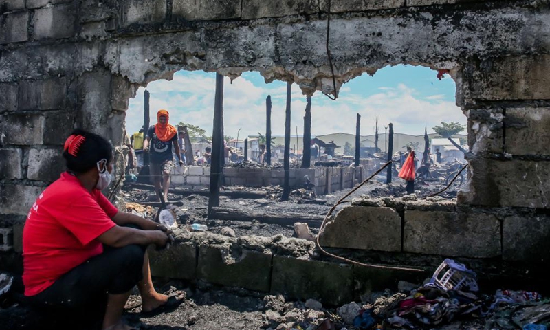 Residents search for their belongings from their charred homes after a fire at a slum area in Rizal Province, the Philippines on March 26, 2021. The Philippine Bureau of Fire Protection said that the fire is believed to have started from one of the houses that was being used as a garment manufacturing area, leaving more than 170 families homeless in the fire.Photo:Xinhua